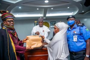 Governor Yahaya BELLO accompanied with DIG Ayuba Ede and the HRH Alhaji Abdulrazaq Isah Koto while presenting Keys and house documents to the wife of his late Escort Out rider, Inspector Aminu Salisu in Government House, Lokoja