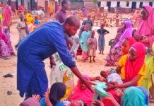 Lawan Bukar Maigana distributing food to nursing mothers affected by the floods at Uwais Alqarni Islamic School in Maiduguri