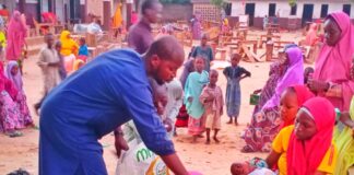 Lawan Bukar Maigana distributing food to nursing mothers affected by the floods at Uwais Alqarni Islamic School in Maiduguri