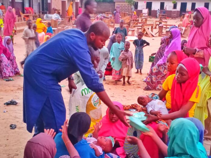 Lawan Bukar Maigana distributing food to nursing mothers affected by the floods at Uwais Alqarni Islamic School in Maiduguri